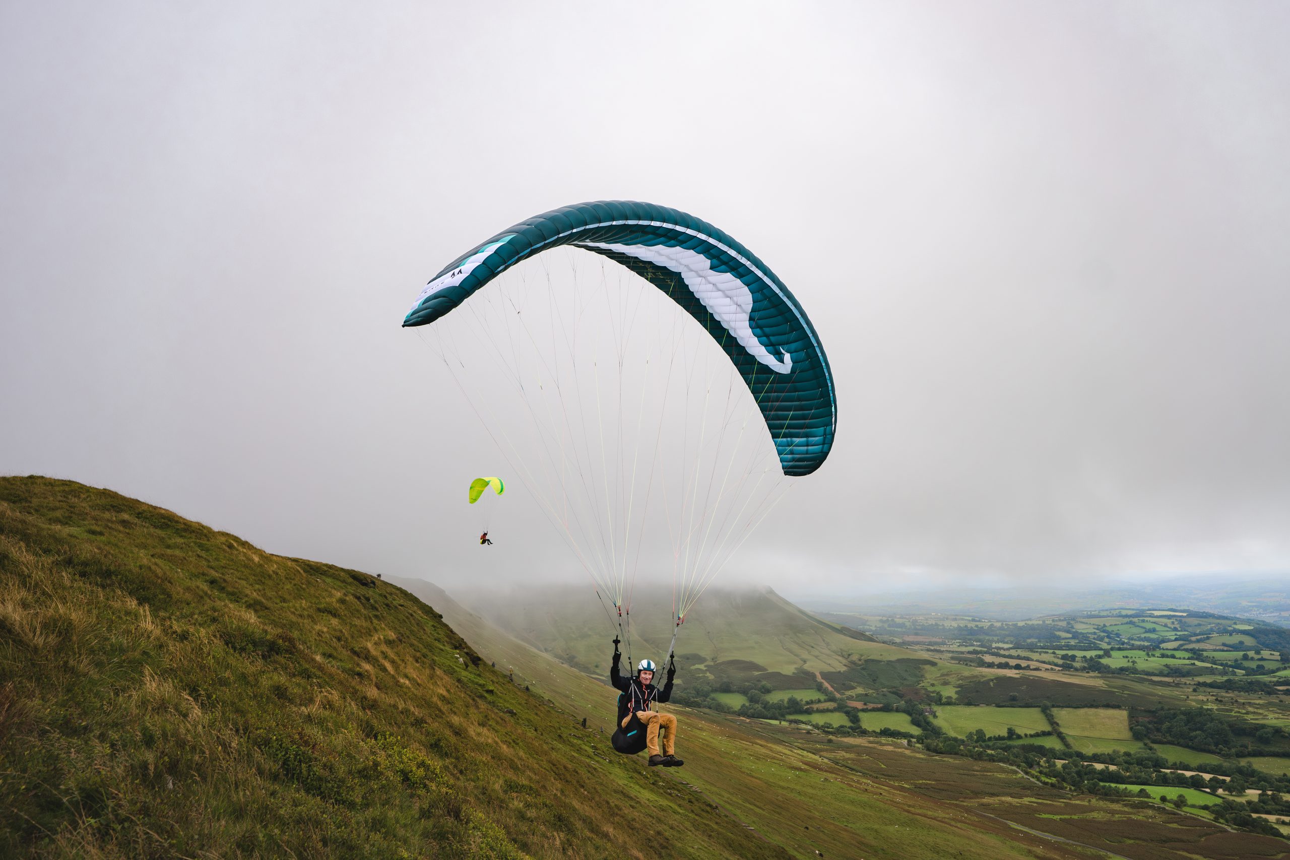 Paraglider launching above a mountain valley in Bannau Brycheiniog National Park.