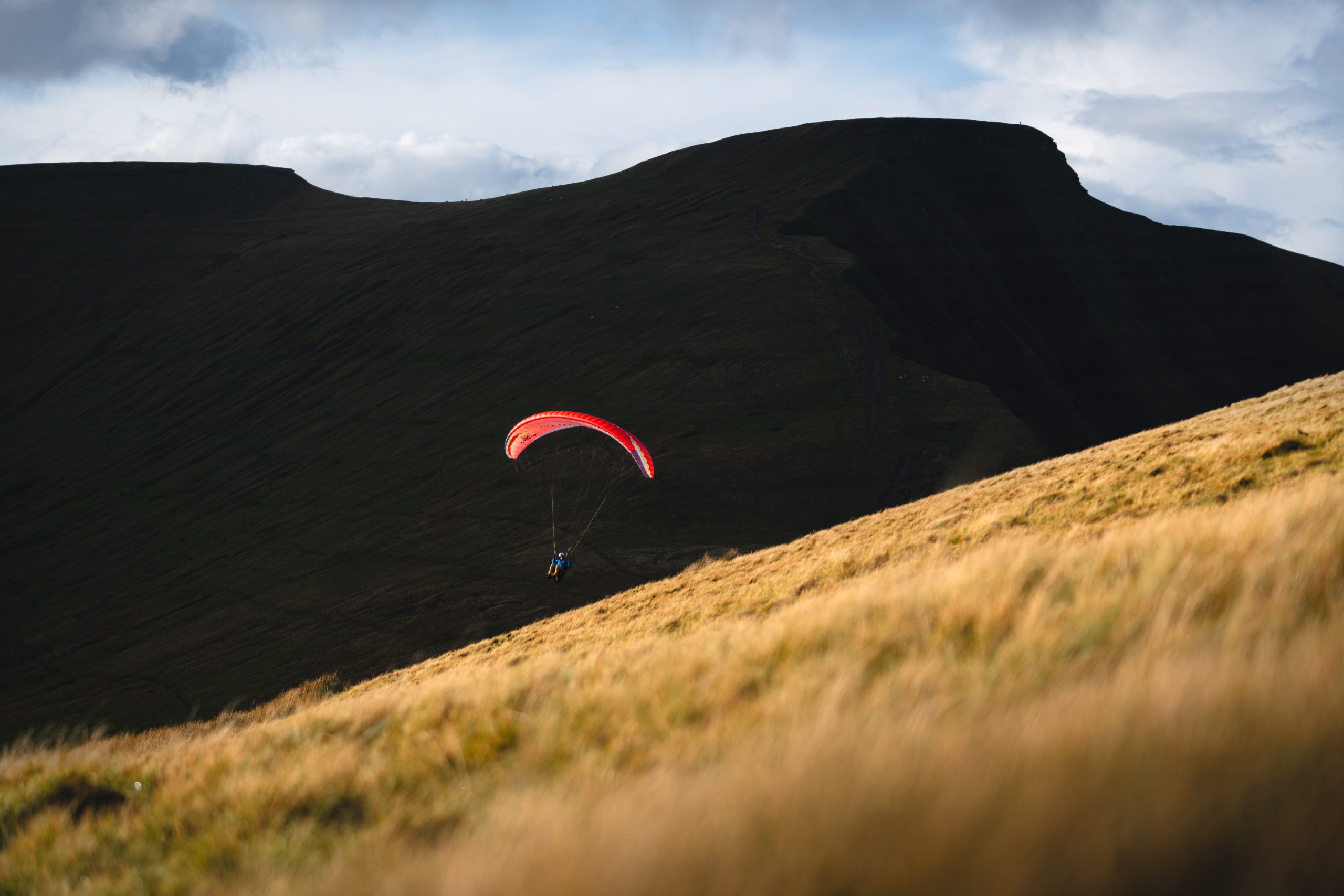 Paraglider flying above the dramatic mountain landscape of Bannau Brycheiniog.