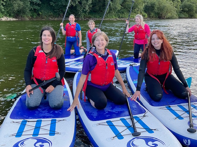Group learning paddle boarding skills on open water.