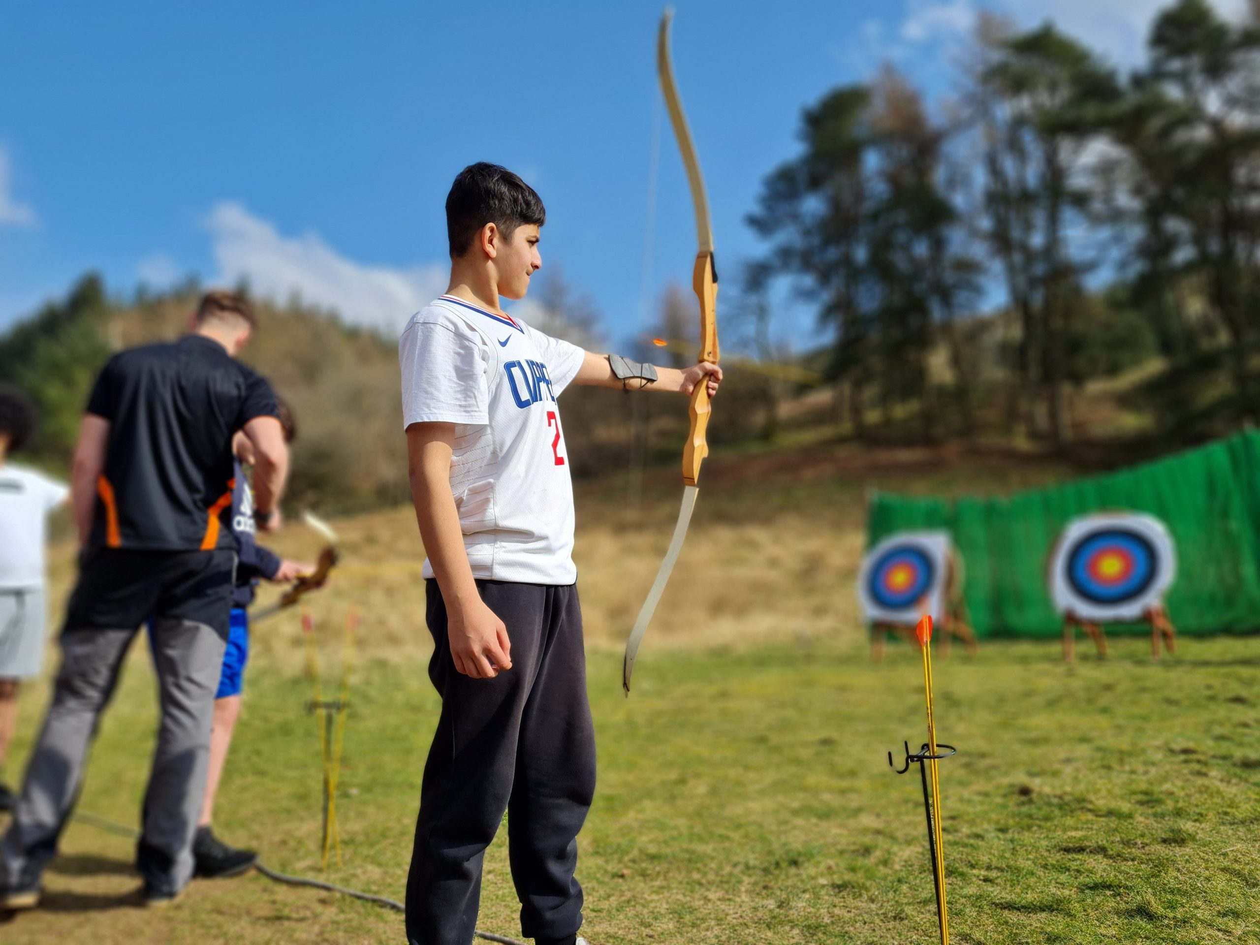 a young man being taught how to use a box and arrow in archery