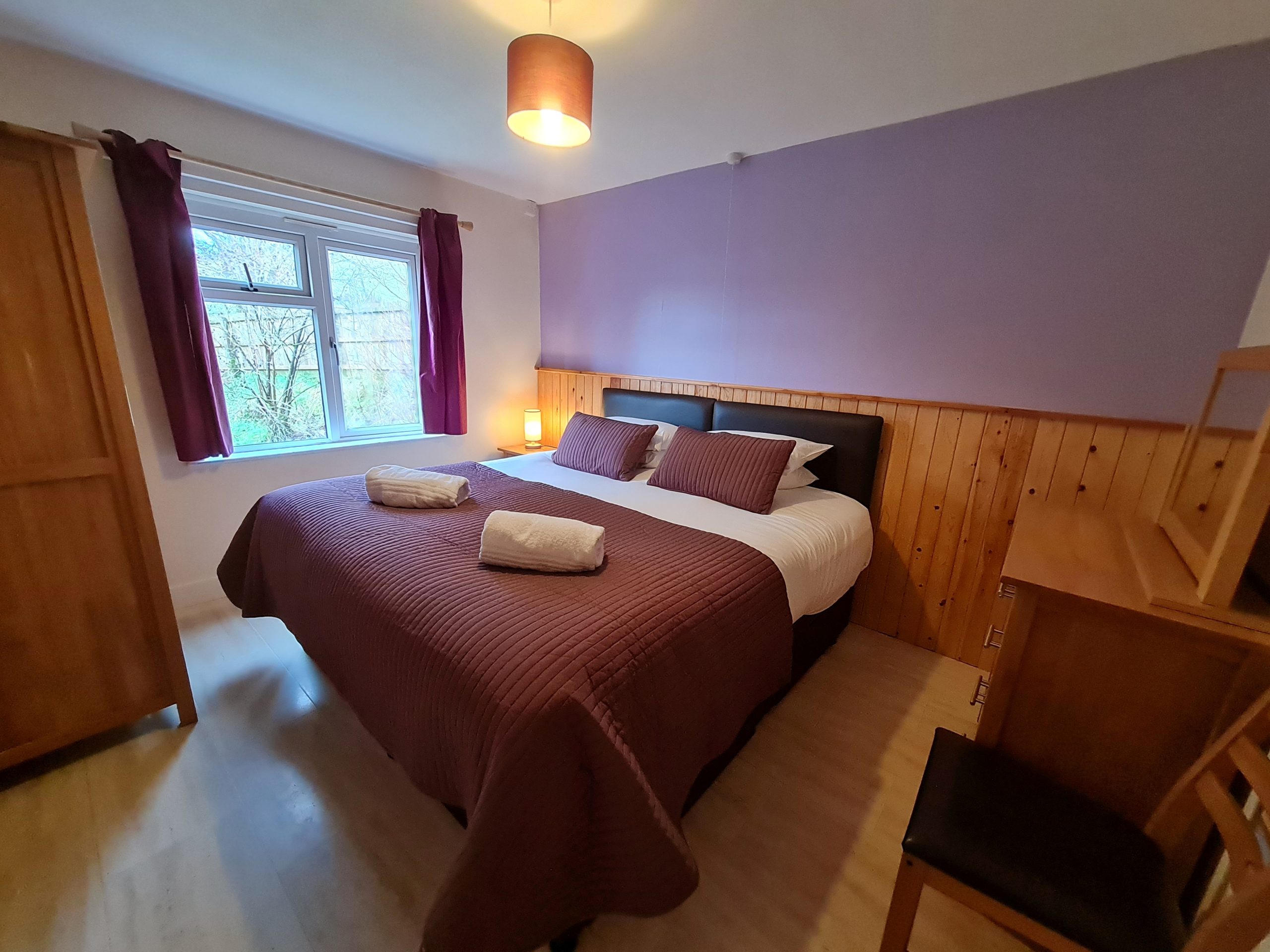 Parkwood Outdoors _ Dolygaer - double room, burgundy bedspread and low lighting