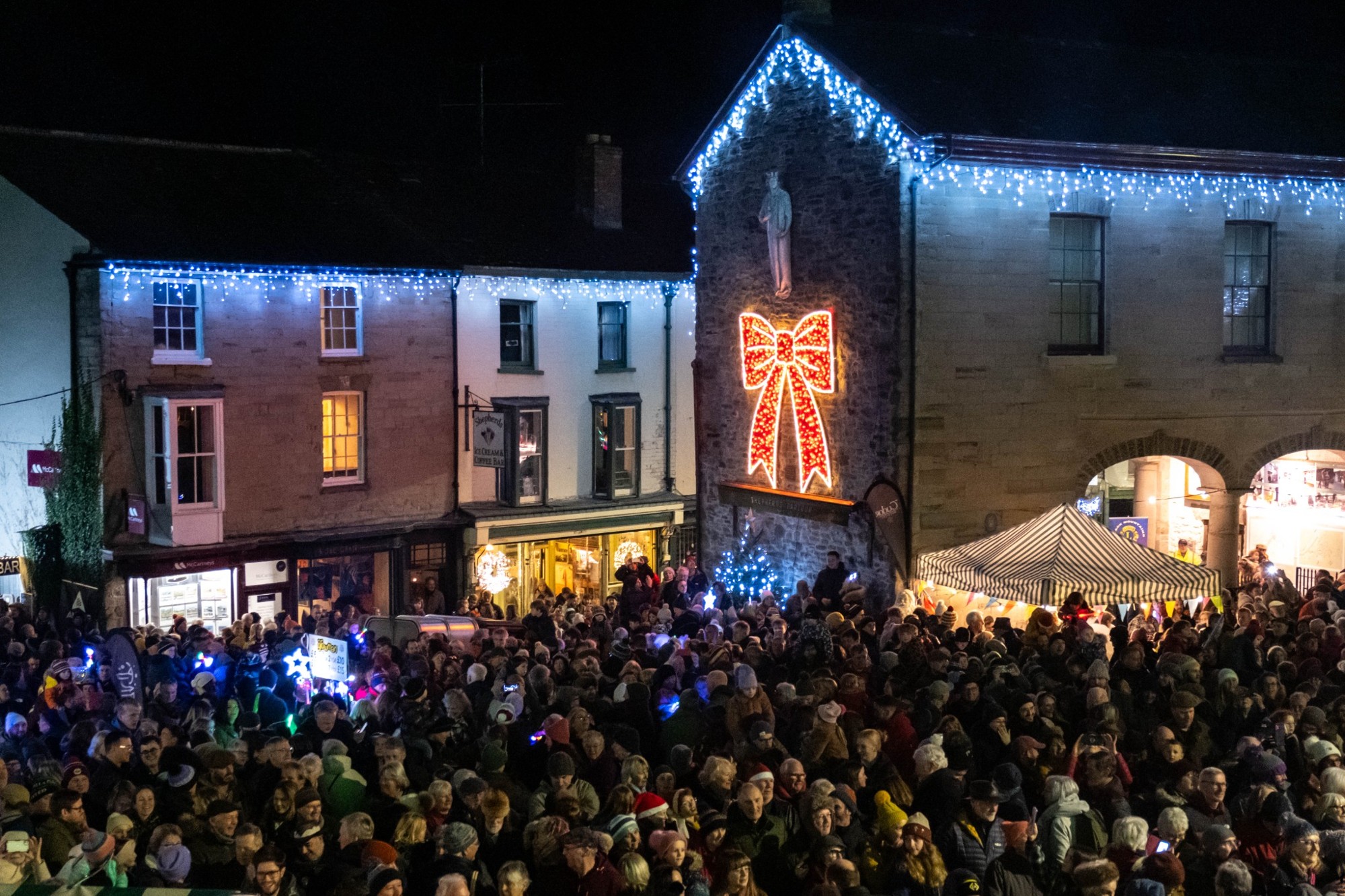 Crowds gathered in Hay-on-Wye beneath Christmas lights and a large illuminated red bow