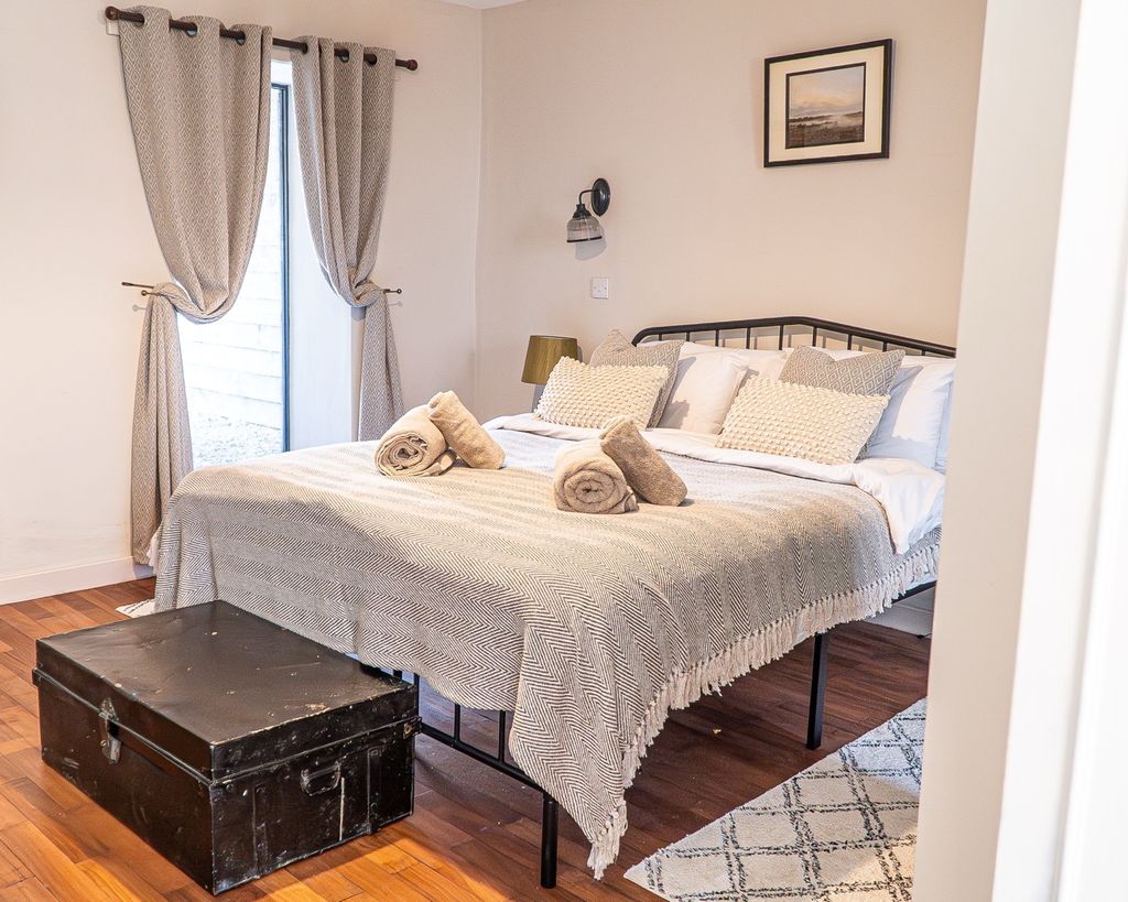 Comfortable double bedroom at Pwll Court Retreat with wooden floors and simple, calm styling.