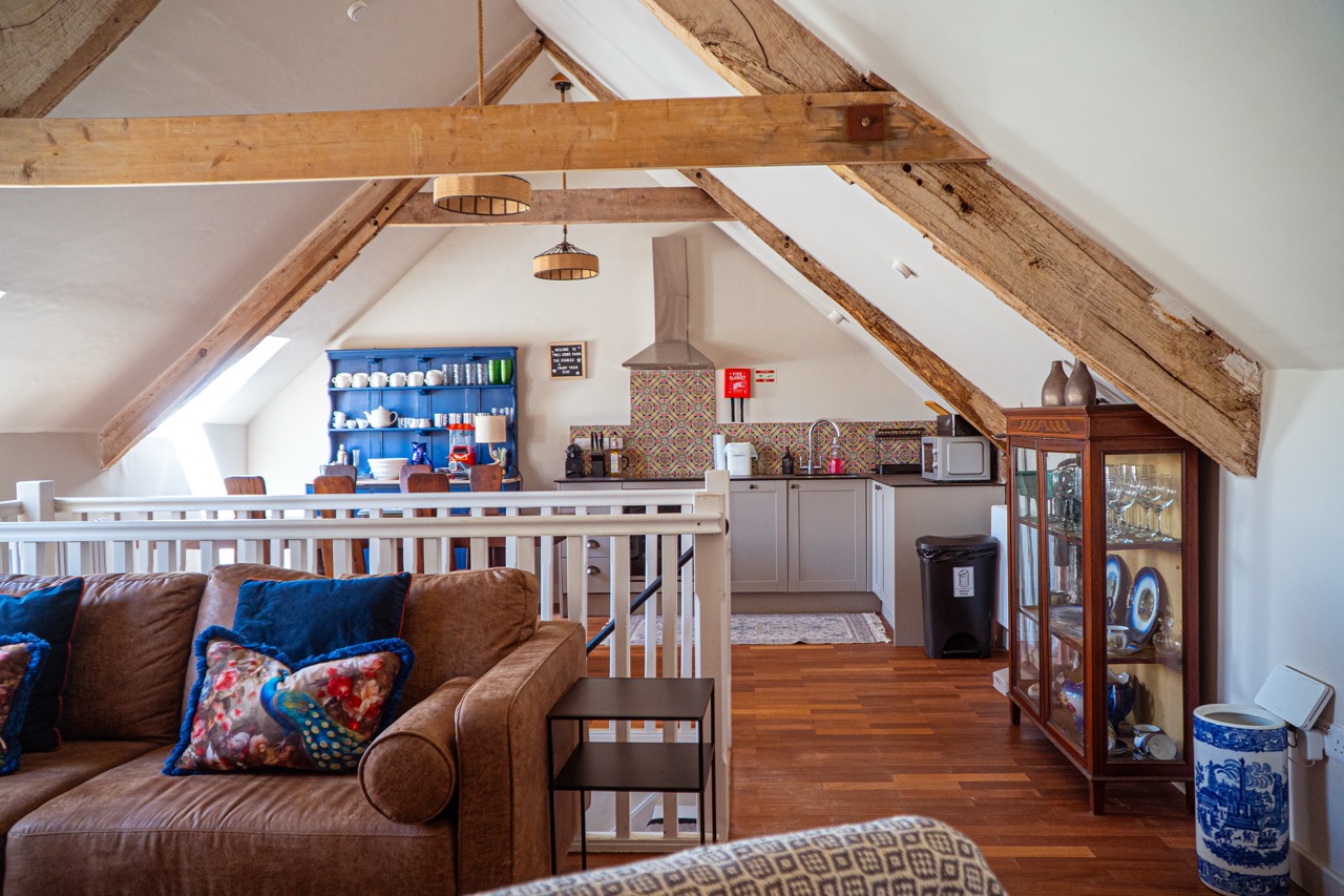 Spacious living and dining area at Pwll Court Retreat with exposed beams and relaxed seating.