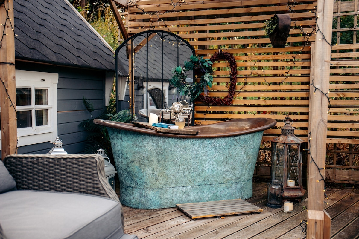 Copper outdoor bathtub beside Ein Trysor Cudd, with timber screening and seating on the deck.