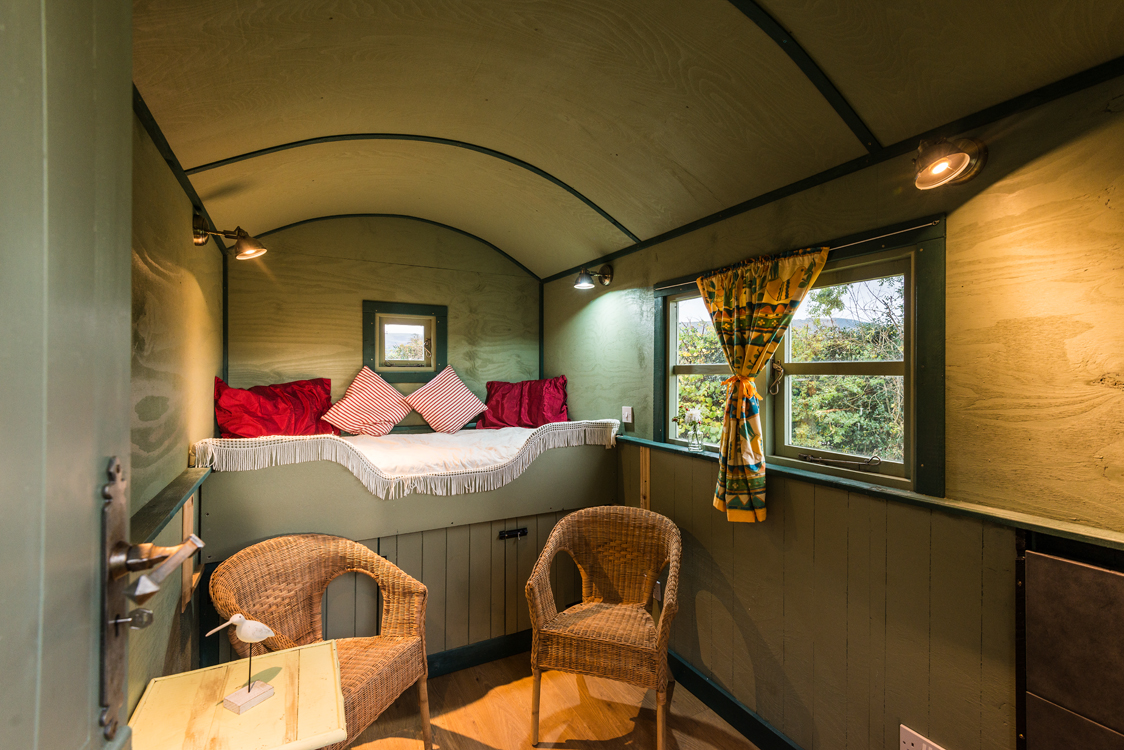 Glamping huts at Shepherds Retreat Wales with views towards surrounding farmland and hills.