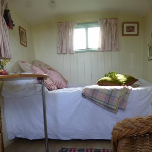 Shepherd’s hut interior showing seating, dining area and sleeping space.