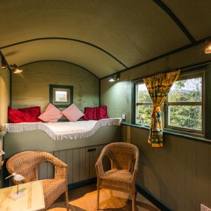 Shepherd’s hut interior showing seating, dining area and sleeping space.