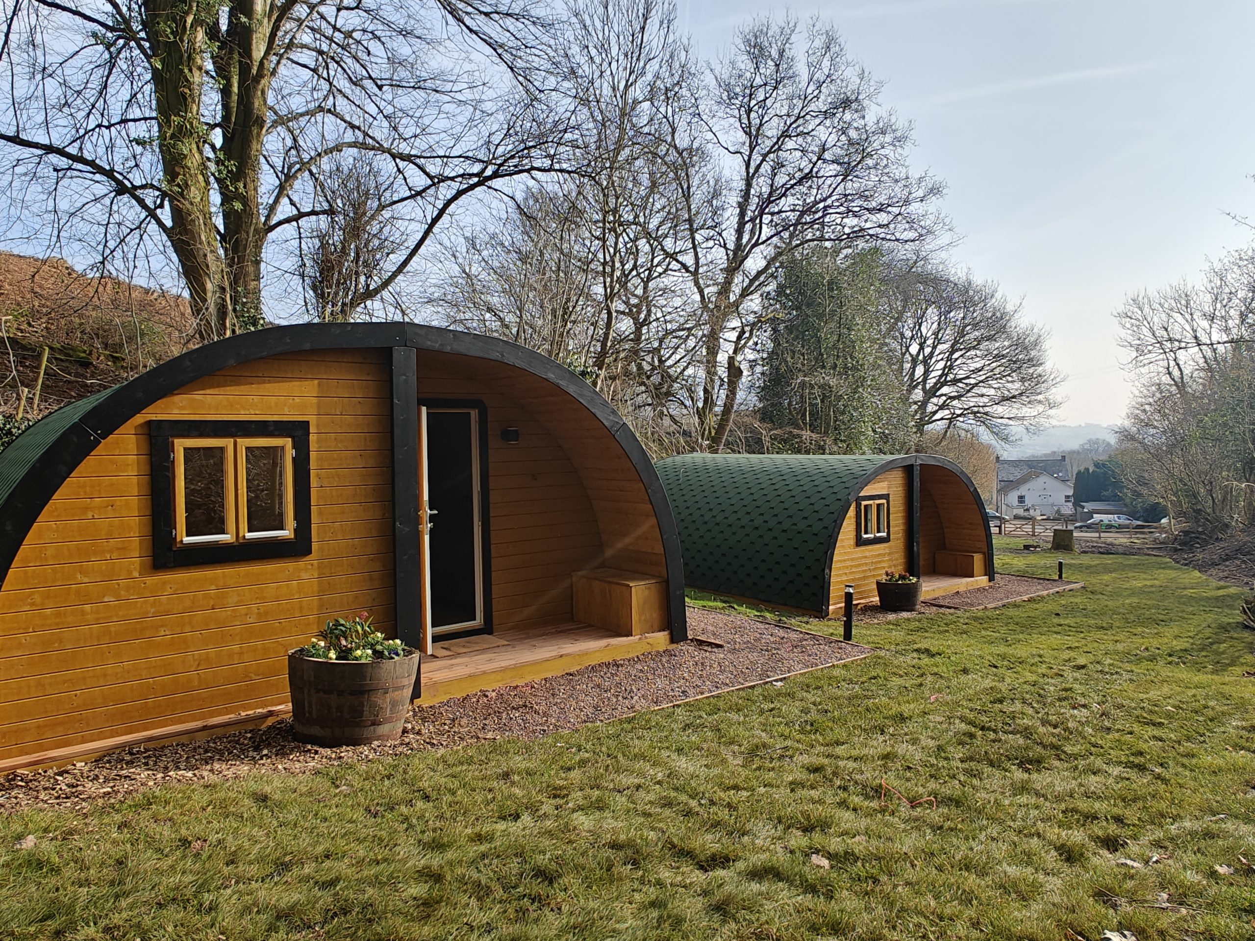 Woodland glamping barrel pods and outdoor seating area in Bannau Brycheiniog (Brecon Beacons) National Park