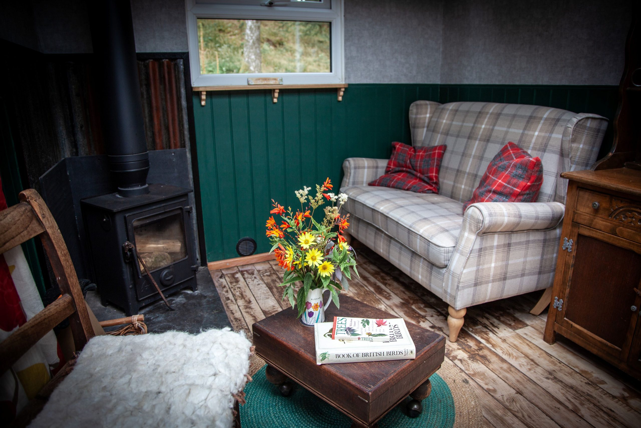 Cosy off-grid living area with wood-burning stove inside Coed Yr Henbont Cabin.