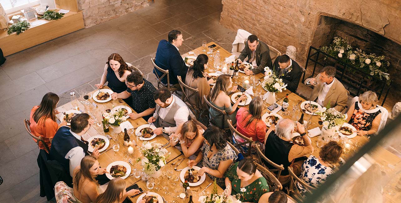 Wedding guests dining at long flower-decorated tables inside Hay Castle