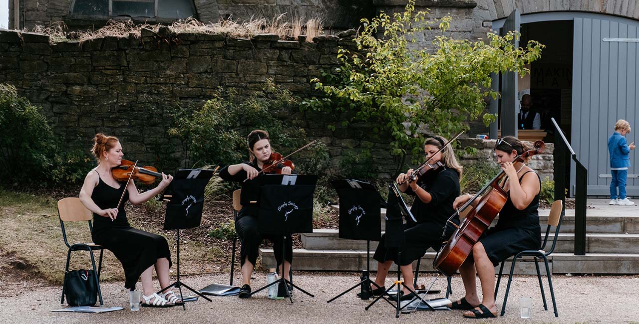 A string quartet performing beside the stone walls of Hay Castle