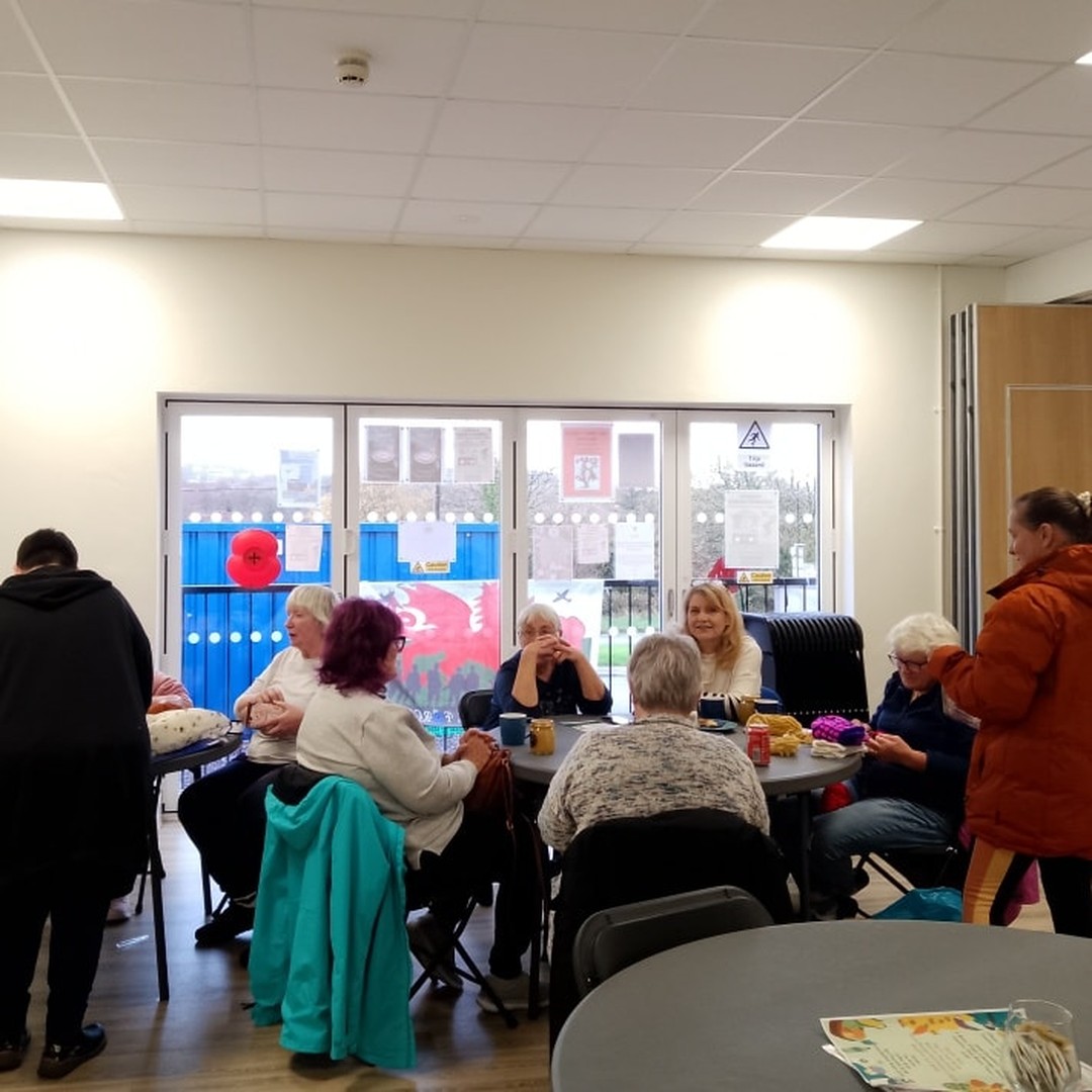 People chatting over drinks around tables inside Penderyn Community Centre