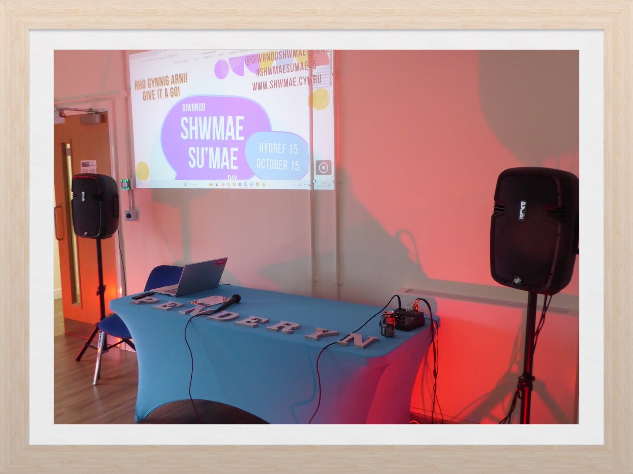 Microphone, speakers and a projected Shwmae Su’mae display set up for an event at Penderyn Community Centre