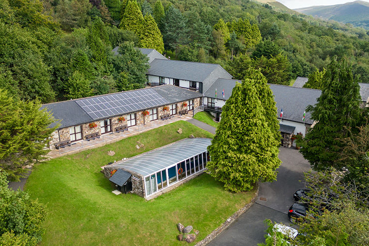 Cottages around a lawn and covered swimming pool at Brecon Beacons Resort.